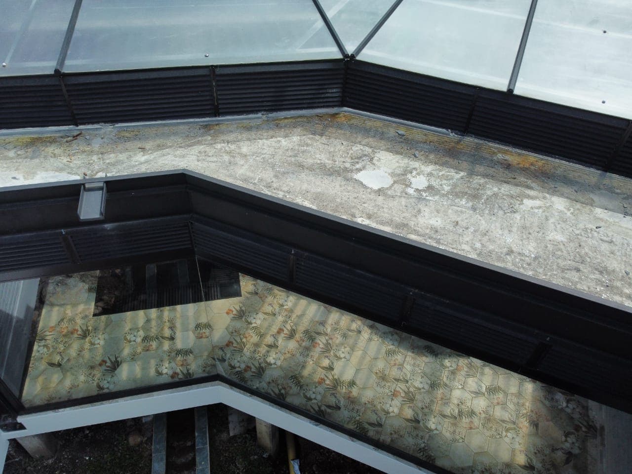 Detalle de soportes y perfiles metálicos bajo una cubierta de vidrio